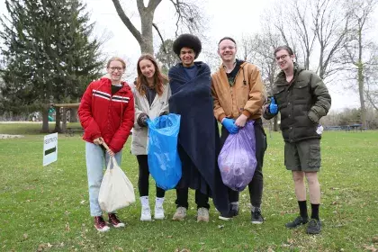 a group of five people posing with bags of litter that they collected