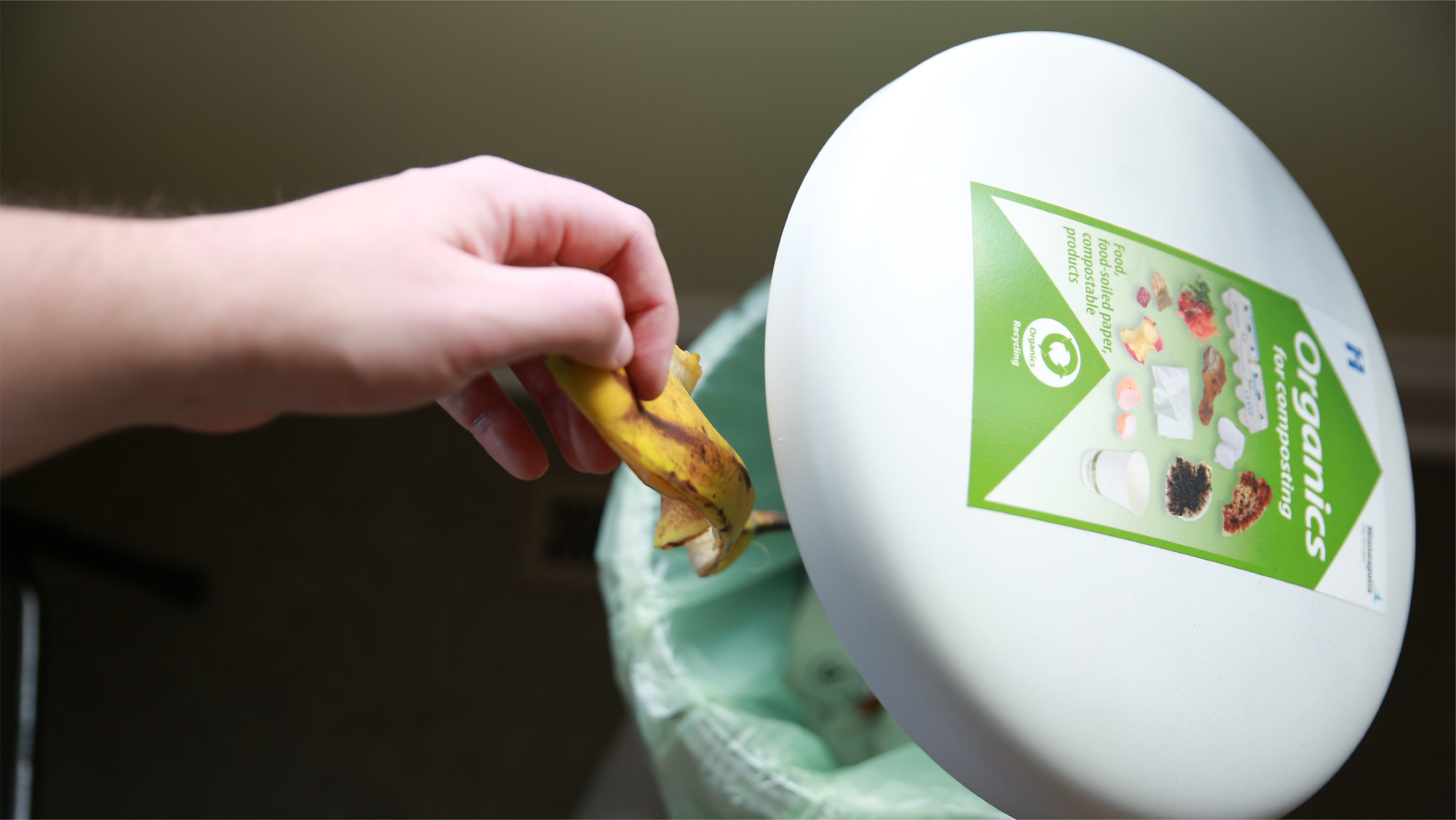 throwing a banana peel in an organics recycling bin