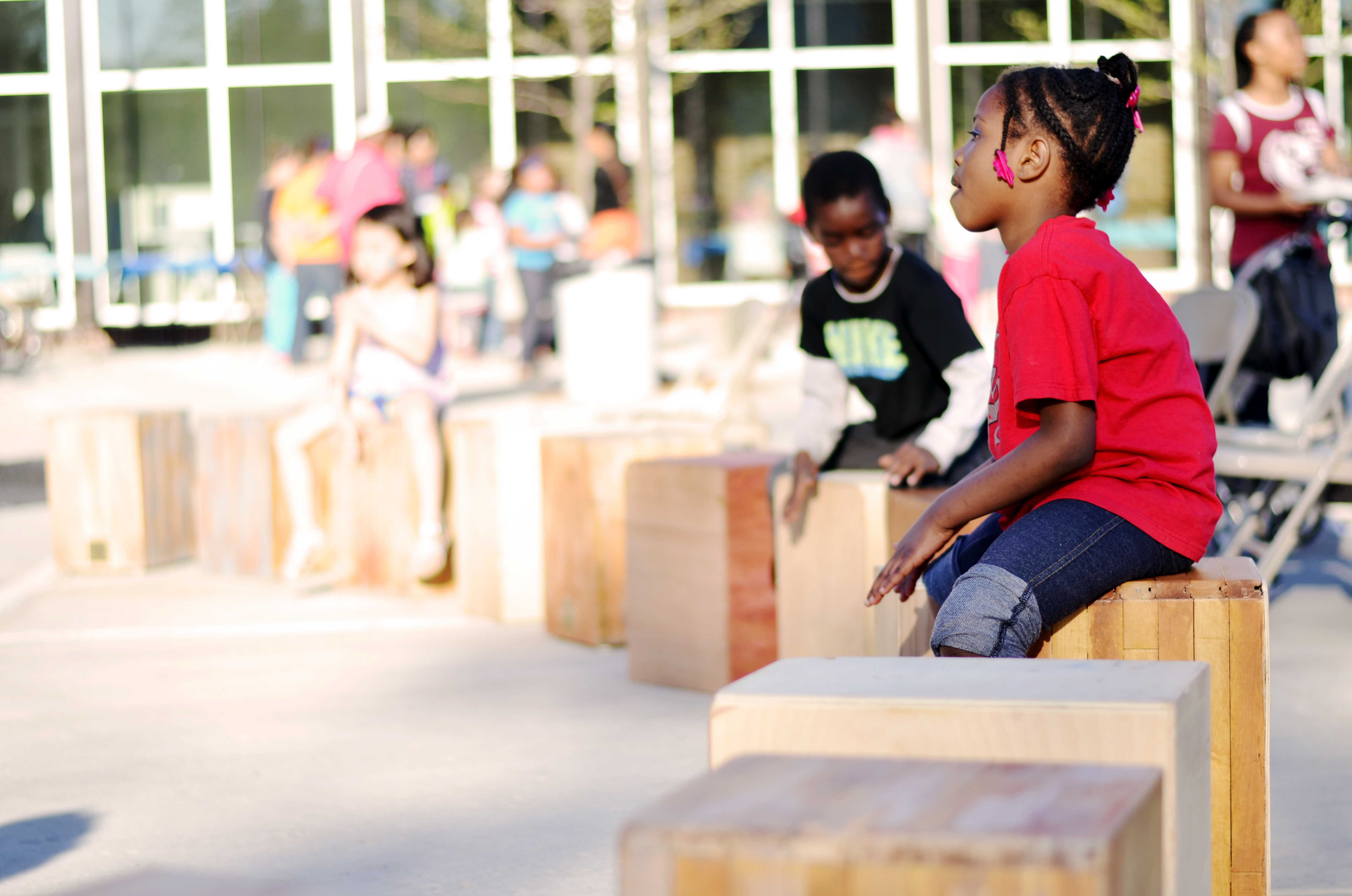 Two children sit on wooden blocks at Arlington Hills Community Center