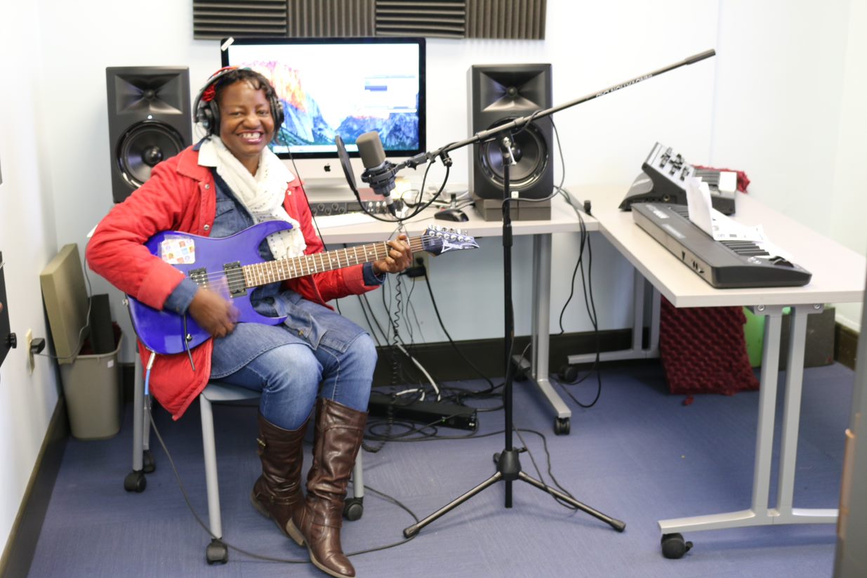 A woman uses a guitar in the Innovation Lab recording studio
