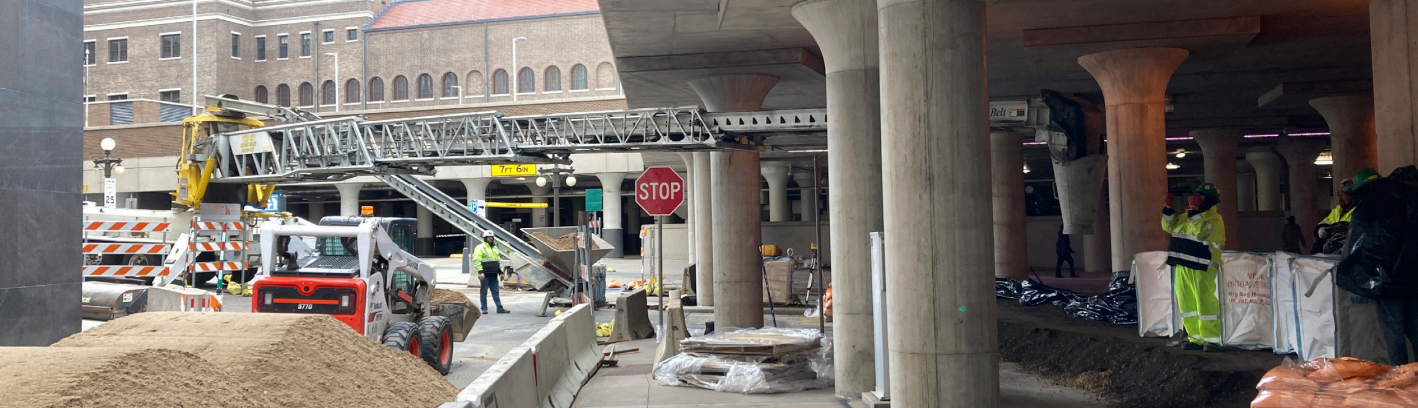 Construction equipment and piles of dirt under a bridge in Lowertown Saint Paul to build a temporary flood wall