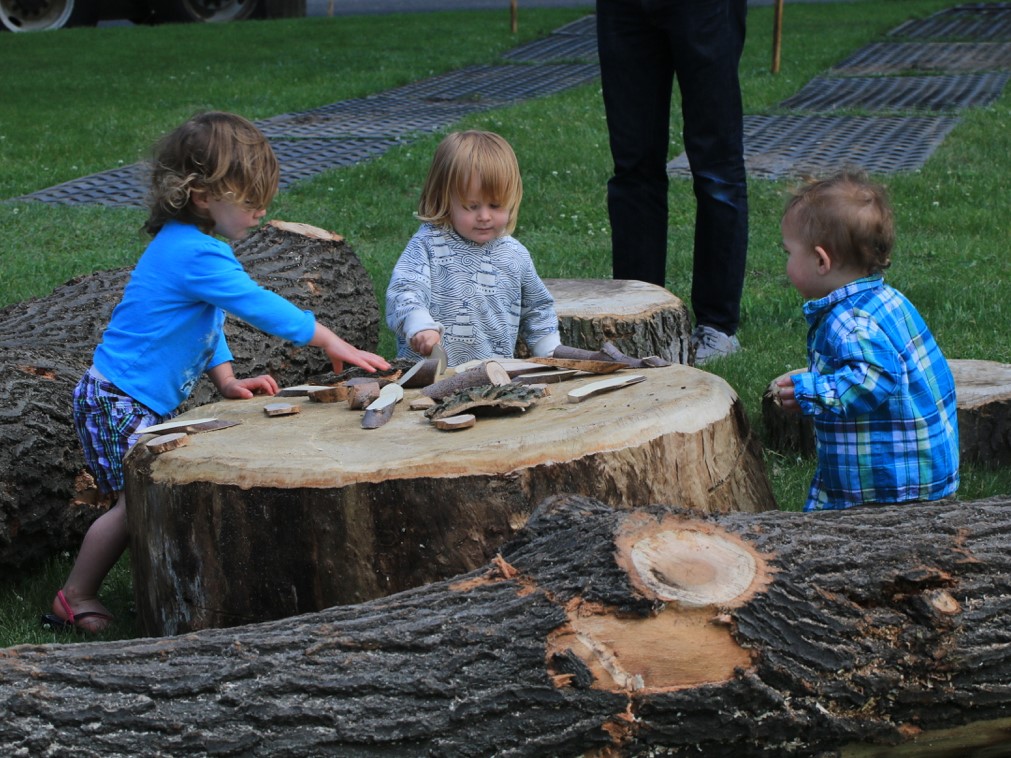 Toddlers playing on wood stump in nature