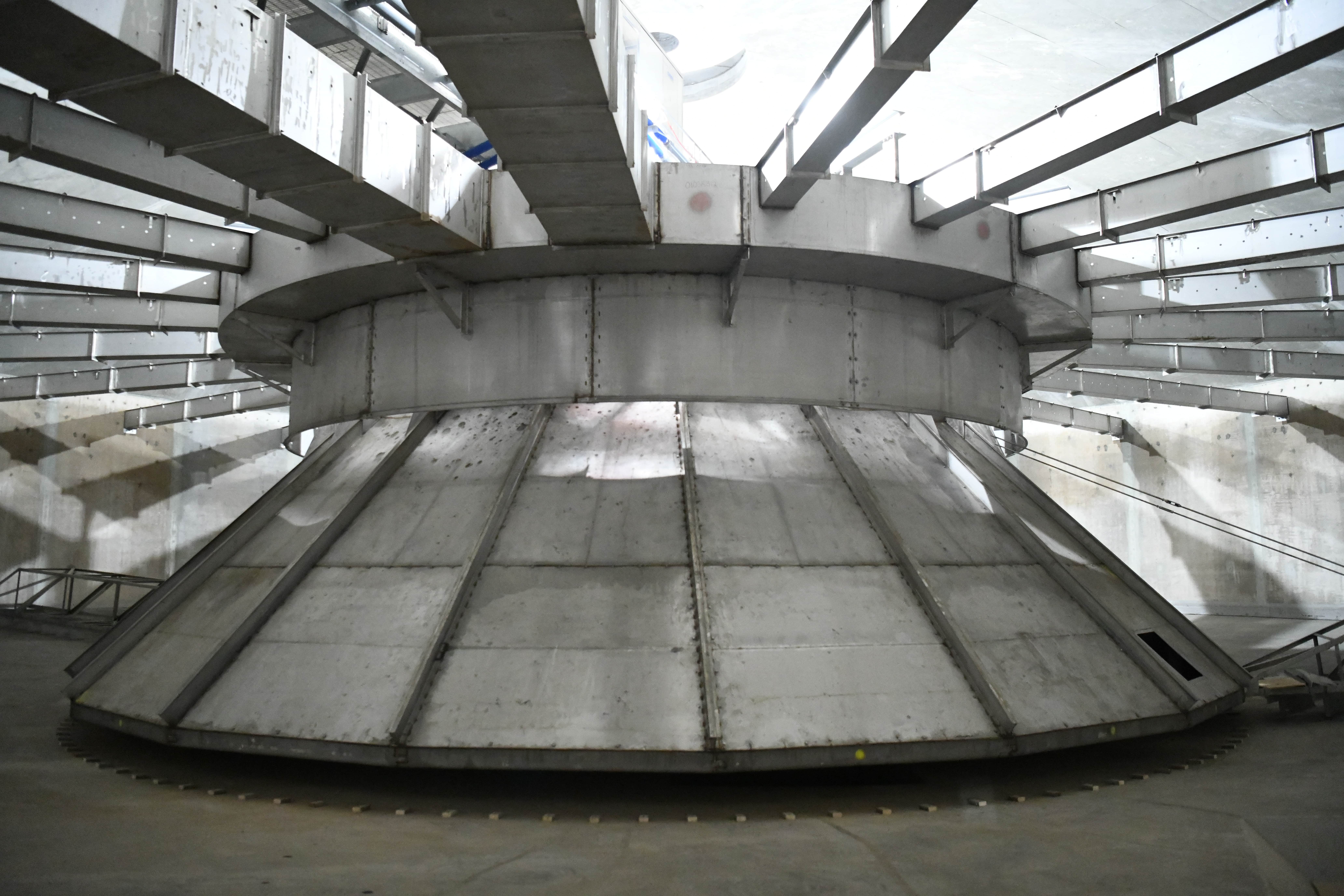 Interior of an empty water clarifier at McCarrons water treatment plant. Large metal structure with radiating metal arms overhead.