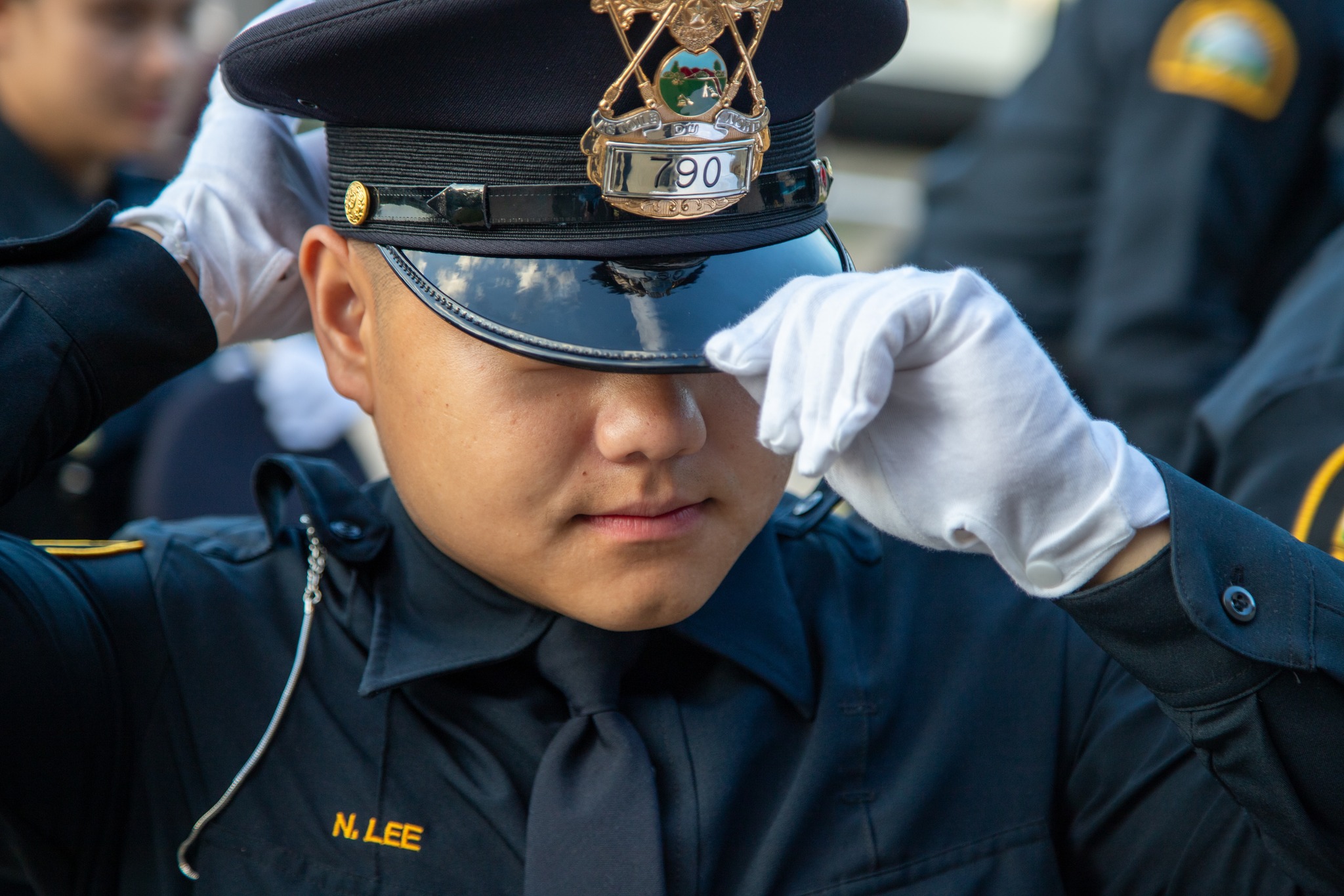 New police officer N Lee touches the brim of his cap at academy graduation ceremony