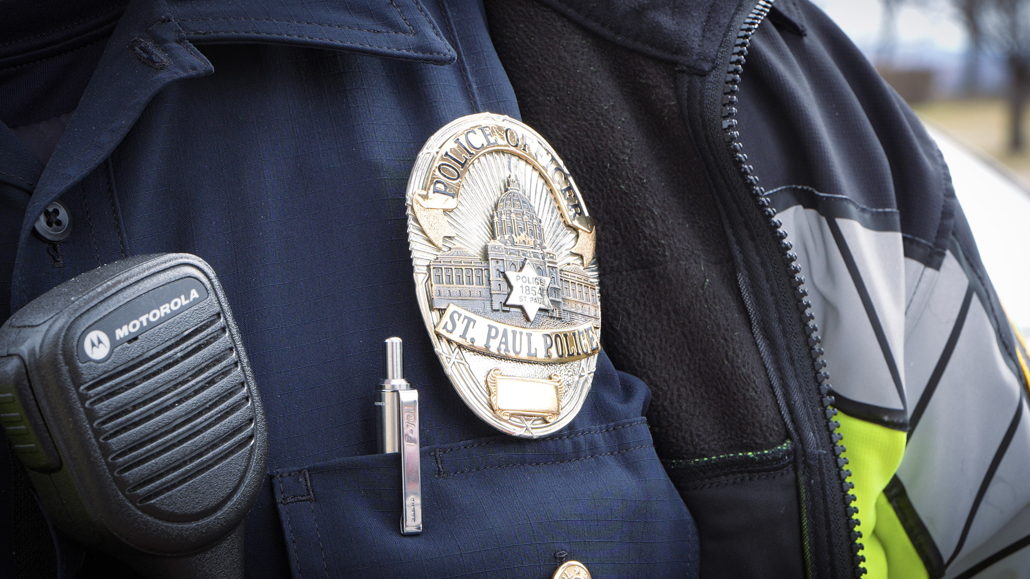 Close up of a police offer badge and radio outside on a snowy day.