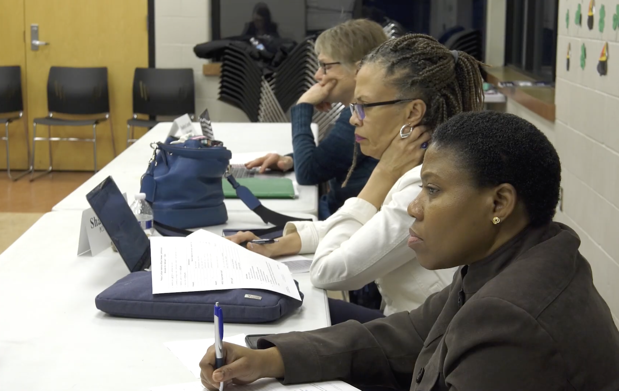 Three women on a commission take notes.