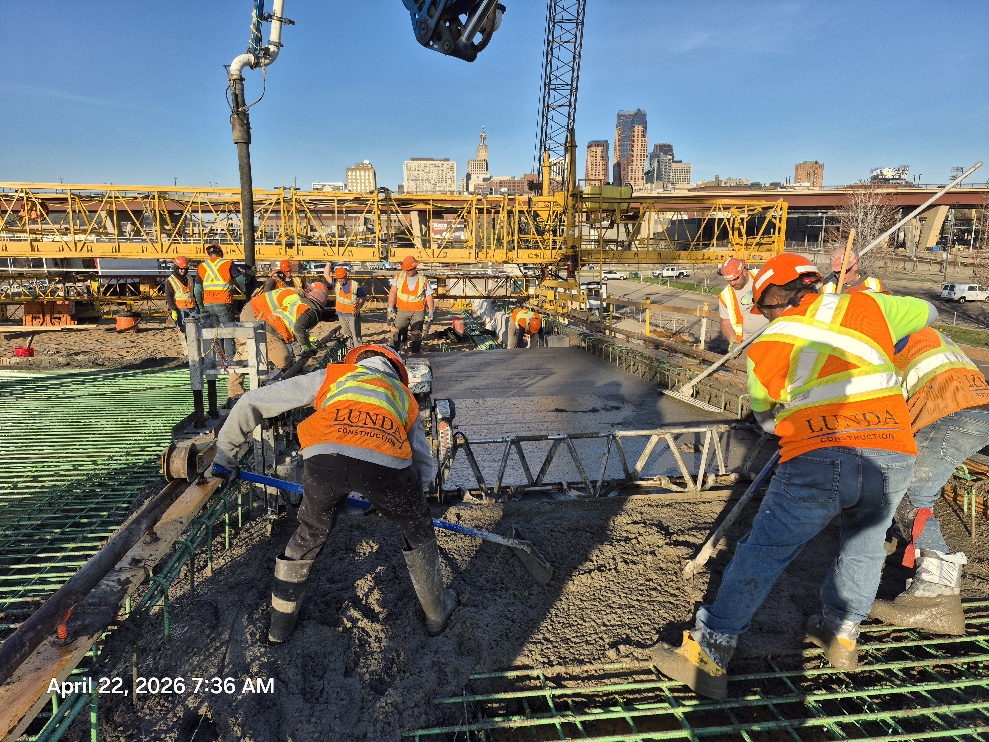 Crews in high visibility vests spreading concrete being poured on the Kellogg-3rd Street bridge on April 22, 2026