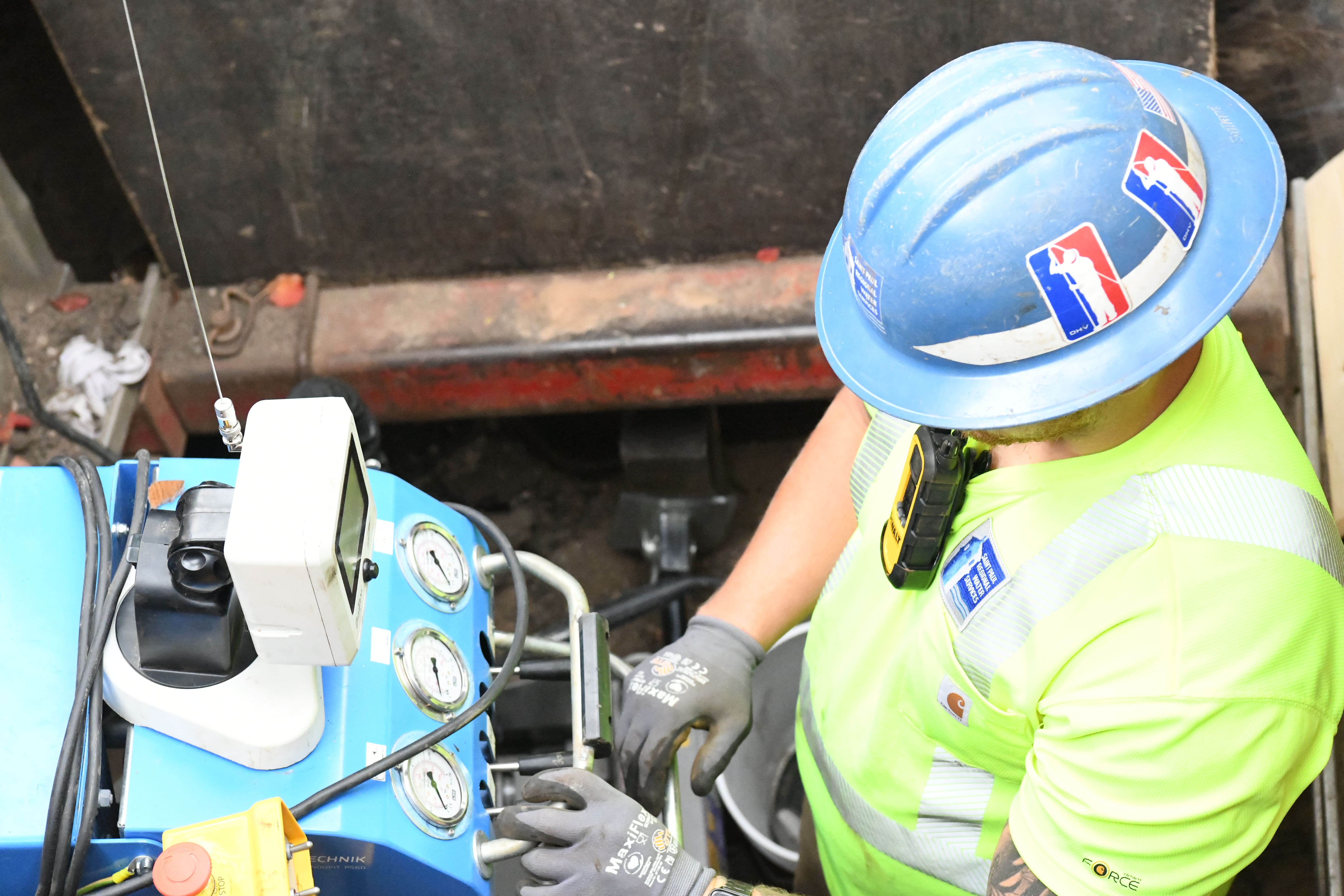 A worker guides horizontal drilling equipment underground to allow for a new copper line to be pulled through from the street to the house during a lead replacement.