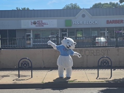 Matoskah, the Bear + Larp District mascot, poses behind an installed district bike rack.
