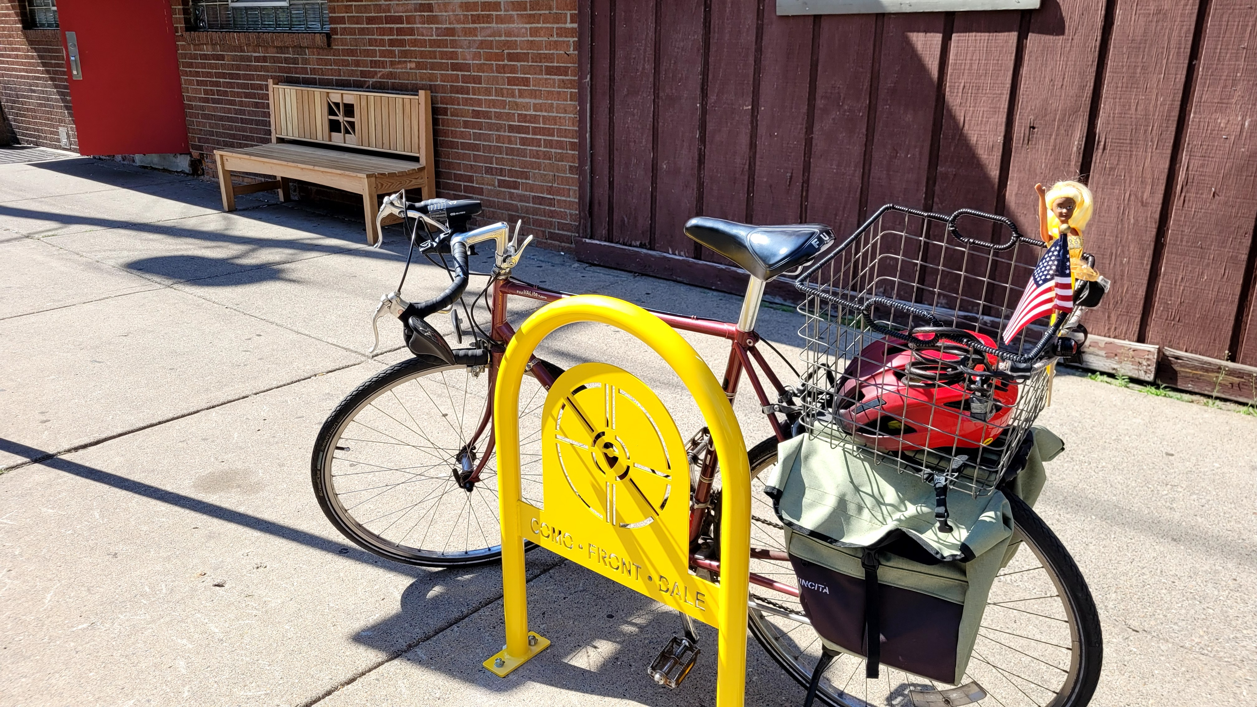 A loaded bicycle parked at a yellow "Como • Front • Dale" bike rack with a wheel cutout design.