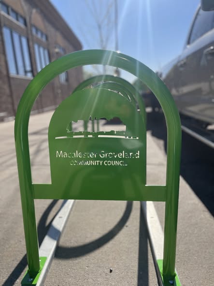 Close-up of a green Macalester-Groveland Community Council bike rack with a cut-out skyline design.