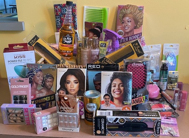Gift basket display of Black hair care, beauty and nail products including bonnets, oils, combs, press-on nails, brushes and styling tools.