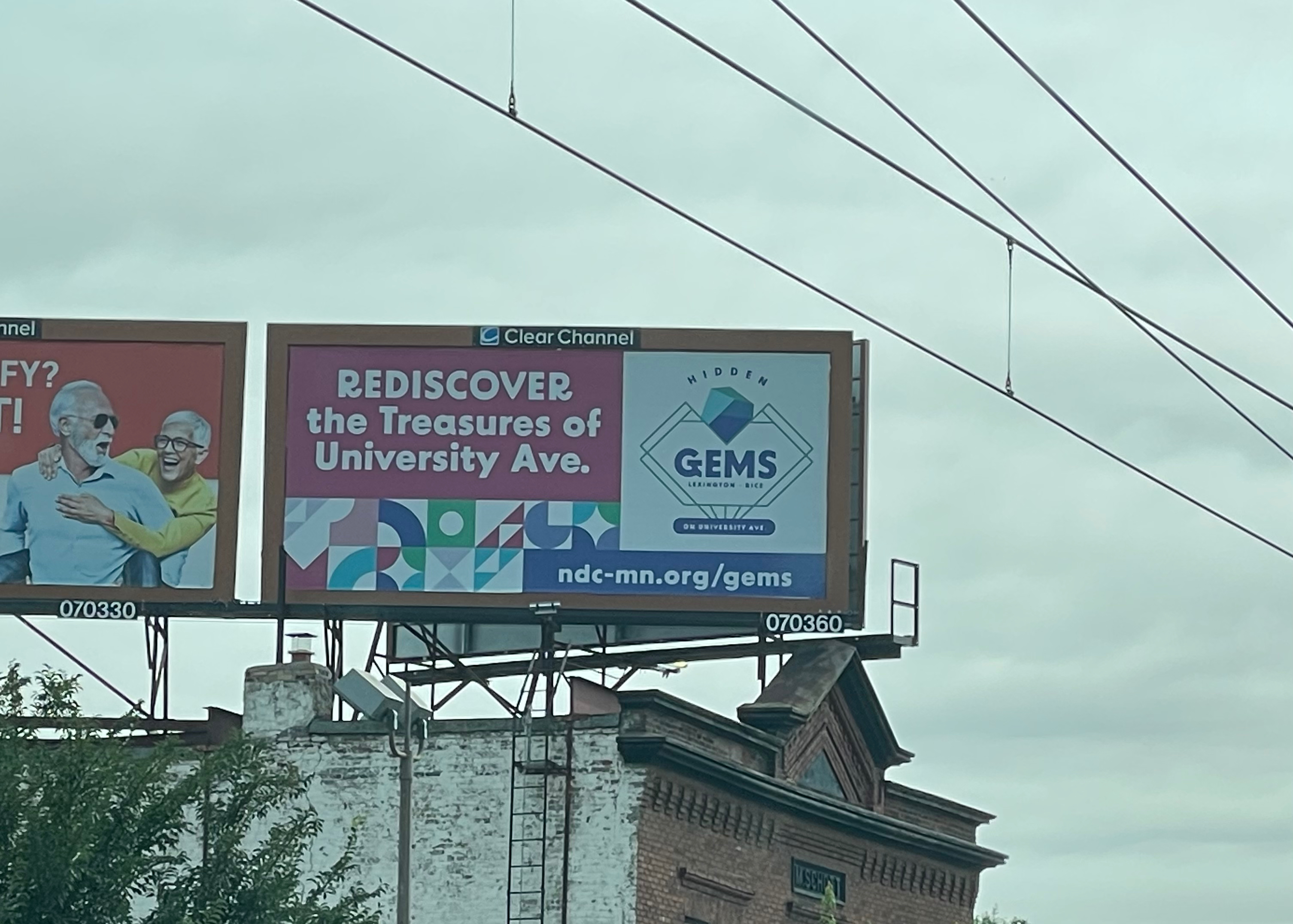 A Clear Channel billboard on University Avenue reading "Rediscover the Treasures of University Ave." with the Hidden GEMS logo and ndc-mn.org/gems URL.