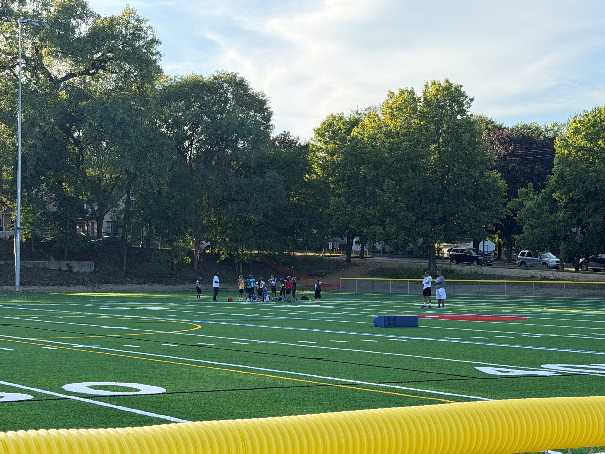 Baker Park artificial turf athletic field, with youth in football gear in a huddle. 