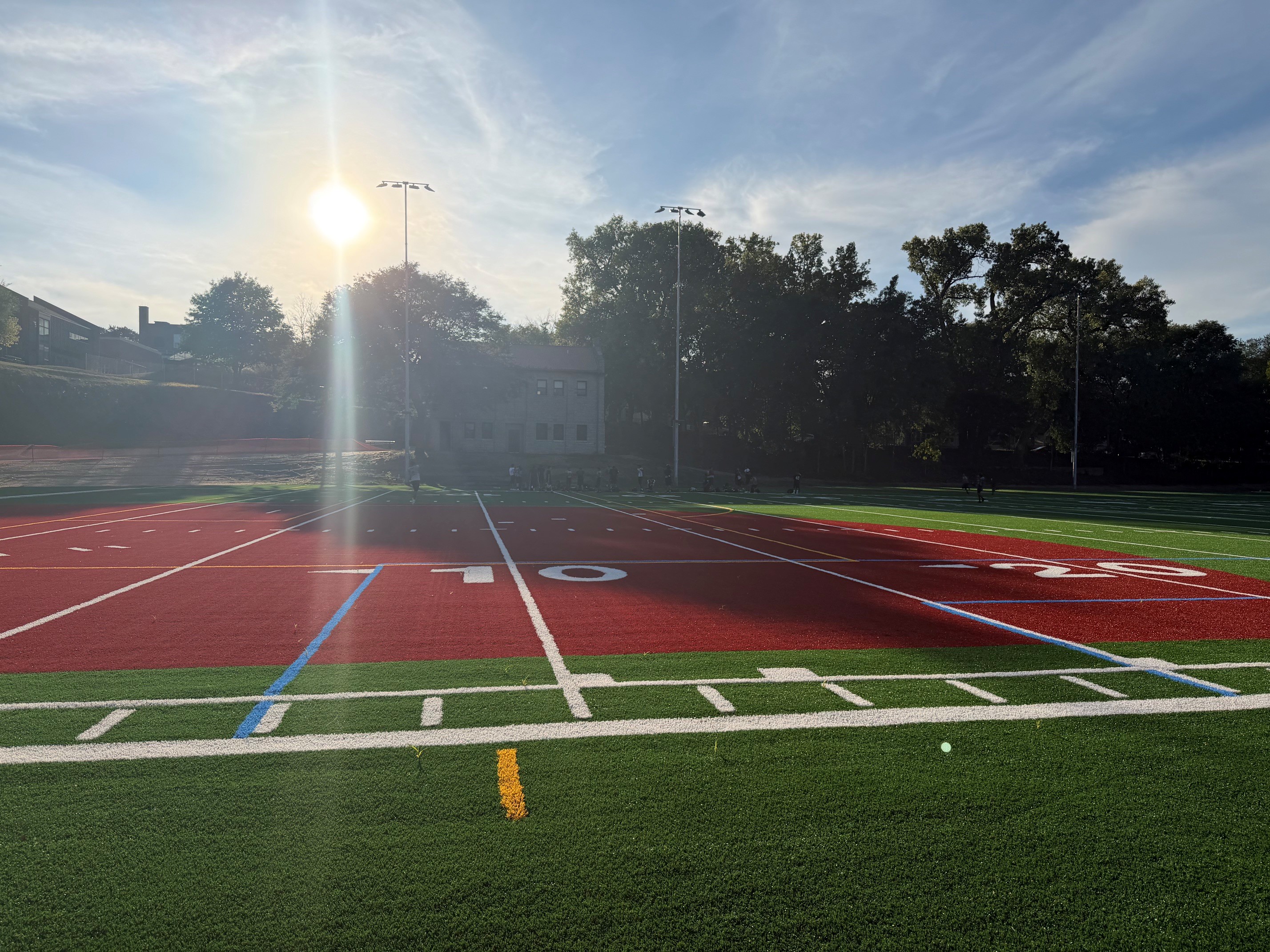 The sun shines over newly installed artificial turf with sports markings. 