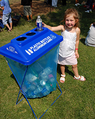 Young girl placing bottle in recycling container
