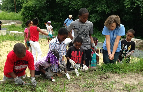 Youth transplanting young sedges and forbs into the propagation garden.