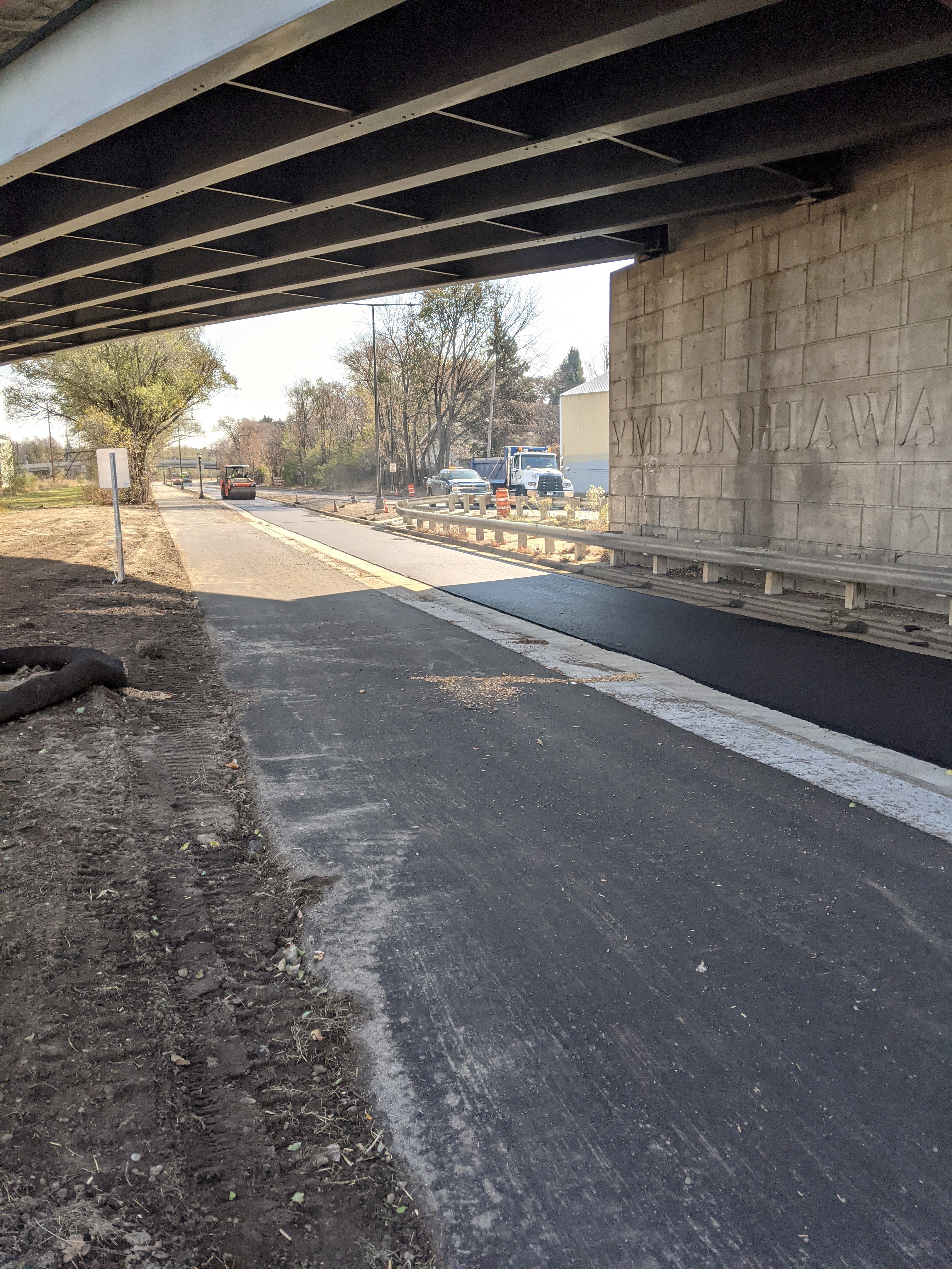 Photo of Ayd Mill Road construction. The photo shows the view facing southbound from under the Selby Avenue overpass from the new trail.  Steel drum roller is compacting freshly placed asphalt on northbound lane.