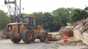 Machinery picking up large pieces of bluff debris from the street.