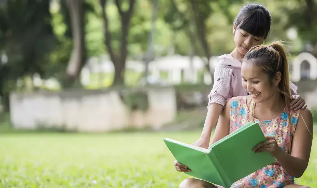 Mother and daughter reading a fairytale to her daughter in the park