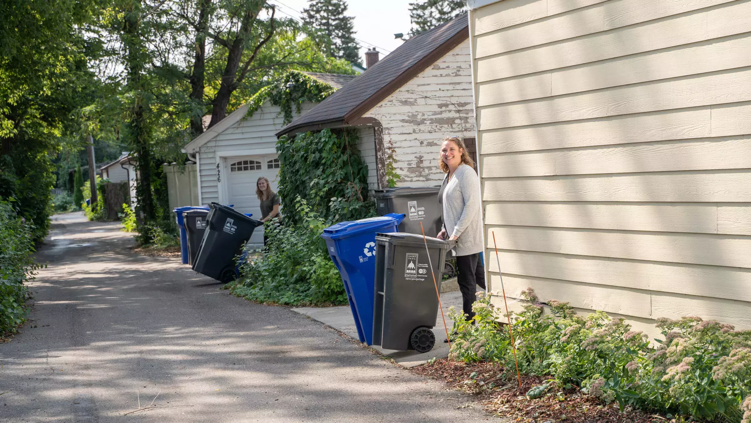 2 women with recycling carts in alley