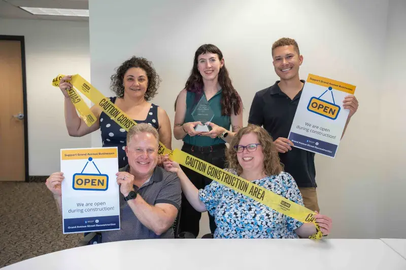 Five staff members hold an award and Open for Business promotional materials.