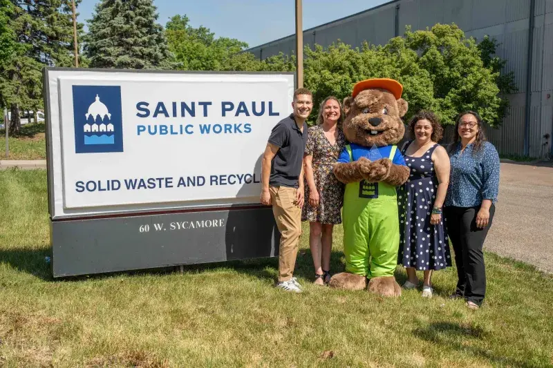 Four employees stand with Sycamore Squirrel mascot holding an award.