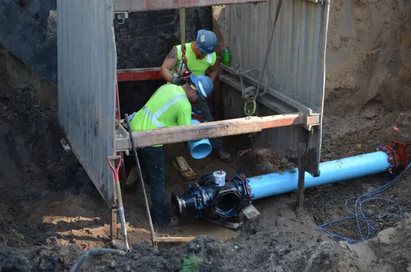 Two SPRWS employees installing water main inside a protective trench box