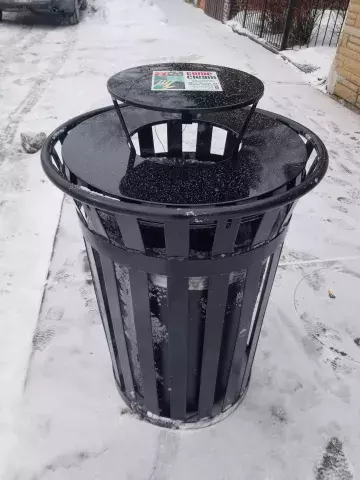 black trash container with lid outside on sidewalk