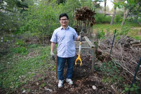 man outside holding pitchfork with dead leaves and brush