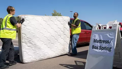 Volunteers lifting mattress for recycling