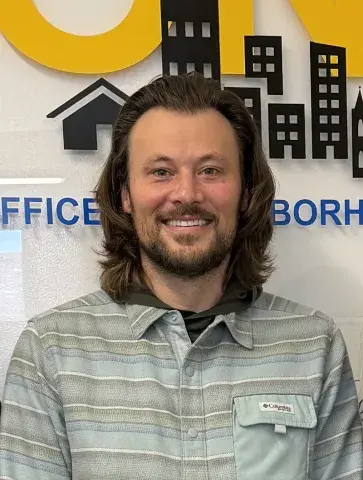 A man with long hair and a beard smiles for a photo