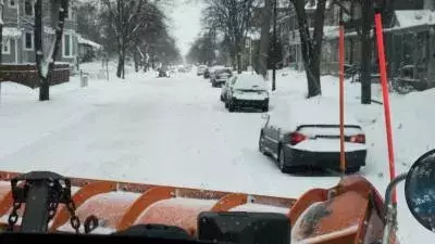 View from a snow plow looking at a residential street before doing "pushbacks" and plowing efforts to clean up extra snow and ice.