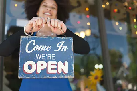 Small Business Owner with "Come In We're Open" sign