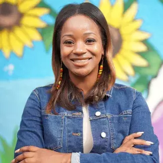 Ward 1 councilmember-elect Anika Bowie smiling in front of a sunflower mural.