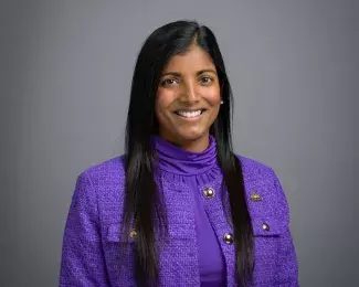 Photo of Ward 3 Councilmember Saura Jost smiling in a bright purple suit in front of a gray background. Photo credit: Rich Ryan.