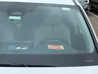 Car windshield with orange Saint Paul residential permit parking visitor pass on dash in front of steering wheel