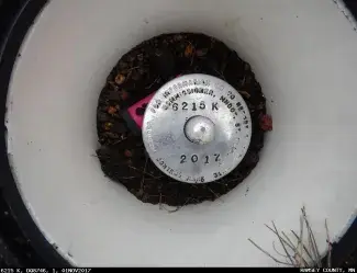 Close-up of a MnDOT geodetic monument, a stamped aluminum disk fitted onto an aluminum rod