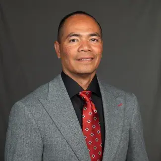 Portrait of a man in a suit and tie against a gray background