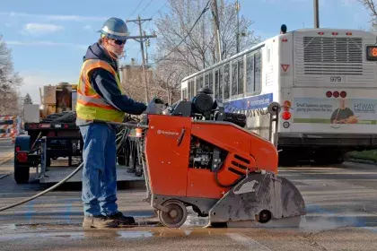 Man cutting pavement with a large wheeled saw