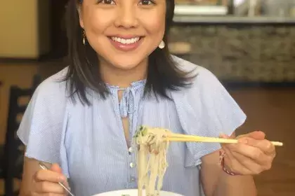 Councilmember Yang eating pho at grand opening of Ifoods Deli on White Bear Avenue E (2021)
