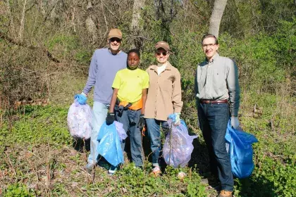 4 people posing with bags of litter that they picked up