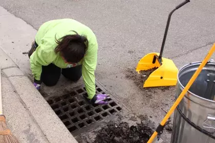 a woman cleaning a storm drain