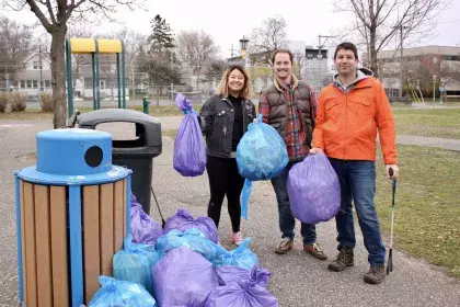 a group of three people posing with bags of litter that they collected