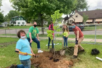 A small group plants a new tree on Arbor Day