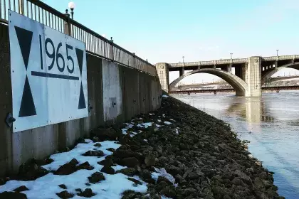 Photo of the historical marker for the 1965 flood on the flood levy south side of the Mississippi River in St. Paul, across from Shepard/Warner Road