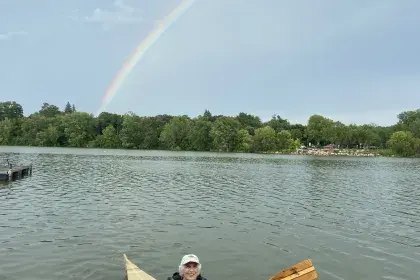 An older adult wearing a life jacket paddles a kayak on Como Lake.