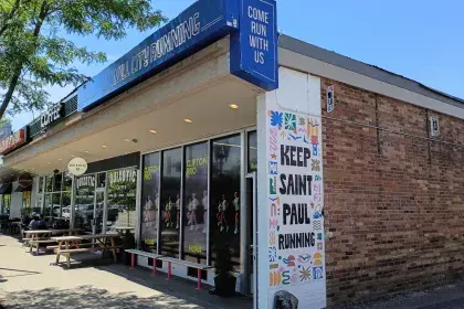 Mill City Running store on a corner with a "Keep Saint Paul Running" mural, next to Quixotic Coffee.