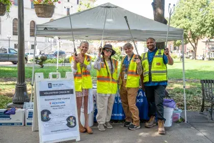 Four people dressed in high vis vests and pointing litter grabbers in the air