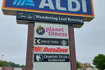 Shopping center pylon sign listing Aldi, Planet Fitness, AutoZone, Dancers Studio, and other West 7th tenants.
